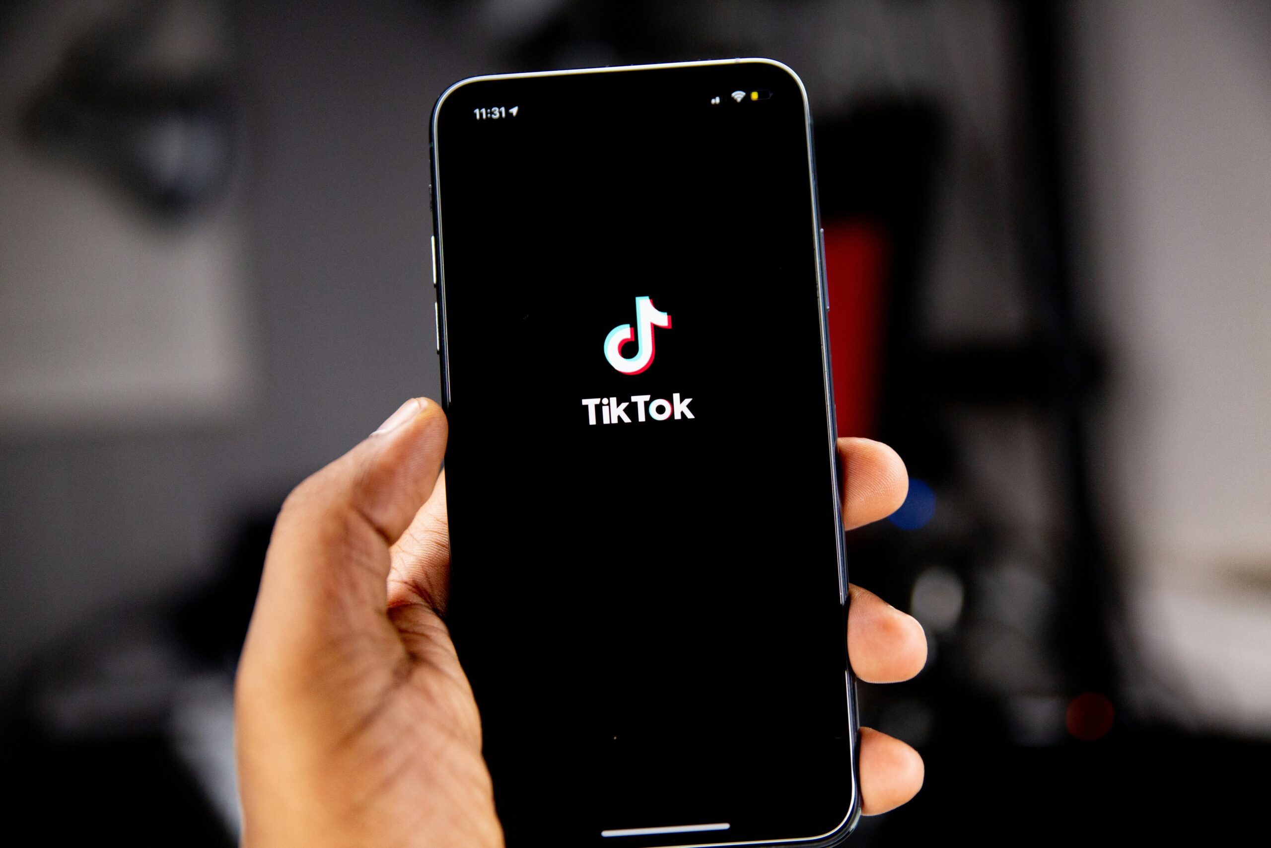 Hand holding a smartphone with the TikTok app loading screen displayed