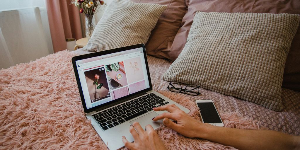 person using macbook pro on bed